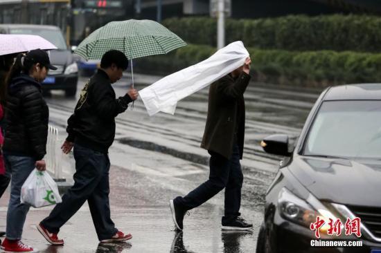 图为民众在雨中出行。中新社记者 贾天勇 摄