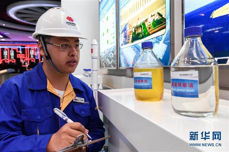 在国家能源集团鄂尔多斯煤制油分公司展厅，一名工作人员观察记录长时间放置的两瓶柴油的性状。左为市场销售柴油，右为煤直接液化产品（4月12日摄）。新华社记者 刘磊