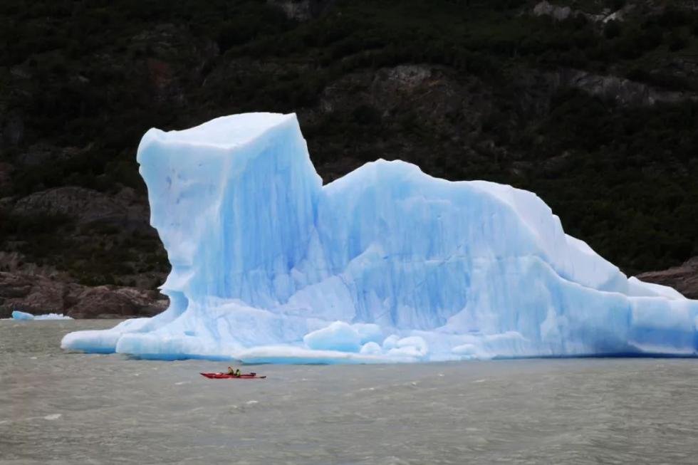 游客在从格雷冰川上脱离的冰山旁划皮划艇。 新华社记者王沛摄