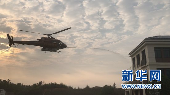 图为消防直升机对着火建筑进行灭火水剂喷射。新华网 黄浩摄