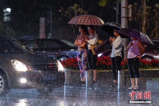资料图：街头行人撑伞挡雨。中新社记者 陈骥旻 摄