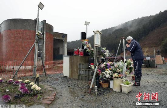 资料图：日本福岛县民众在大地震遇难者墓地哀悼祈祷。
