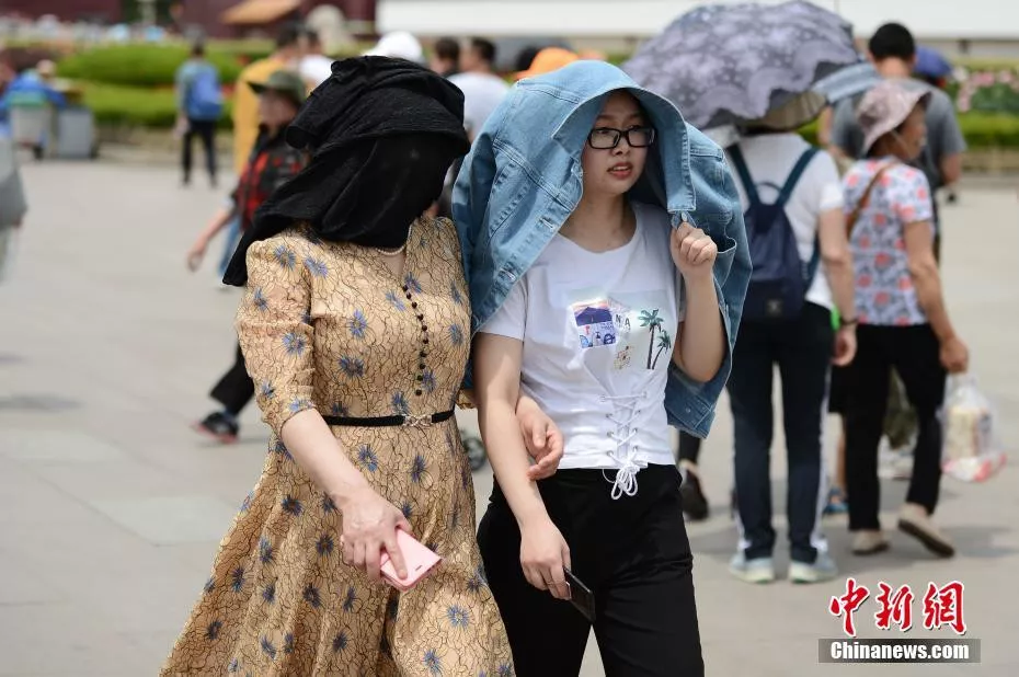 图为5月22日，在北京天安门前游玩的游客“花式”遮阳。中新社记者 张兴龙 摄