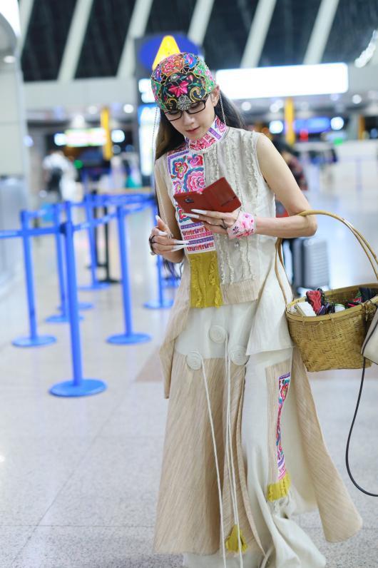 杨丽萍一身米白色的民族风连衣裙现身机场。