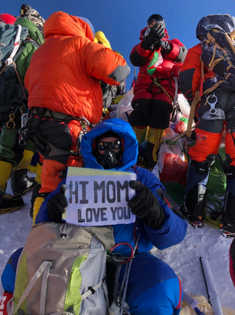 一位登山者在排队中展示标语：妈妈，我爱你。