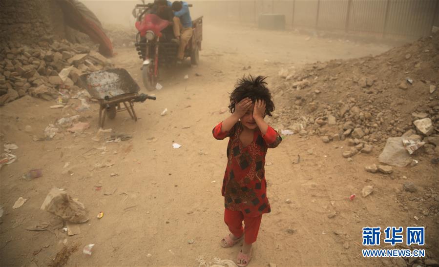 6月20日,在阿富汗首都喀布尔,一名儿童站在难民营前