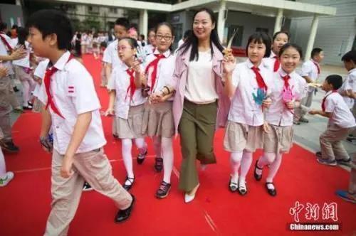 资料图：教师节，老师们牵着学生的手走过红地毯步入校园。张云 摄