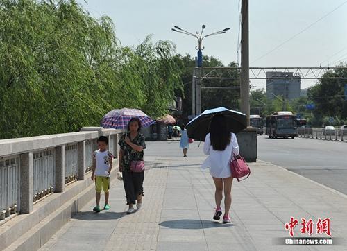资料图:北京进入伏天,高温天气下,市民撑遮阳伞抵挡烈日暴晒。中新网记者 李卿 摄