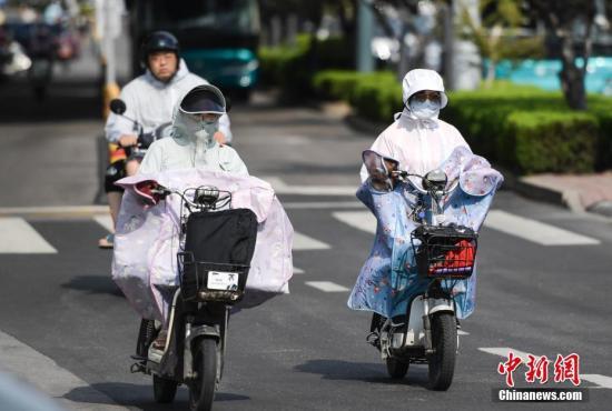 资料图：市民穿戴遮阳防晒装备在高温天气出行。中新社记者 张勇 摄