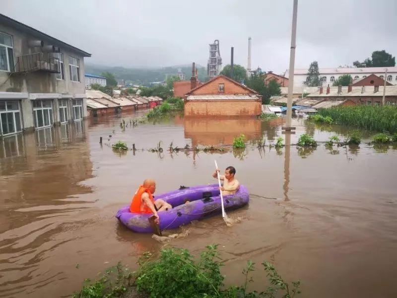 房顶上一位村民被水围困，一辆铲车将该村民从房顶救出。