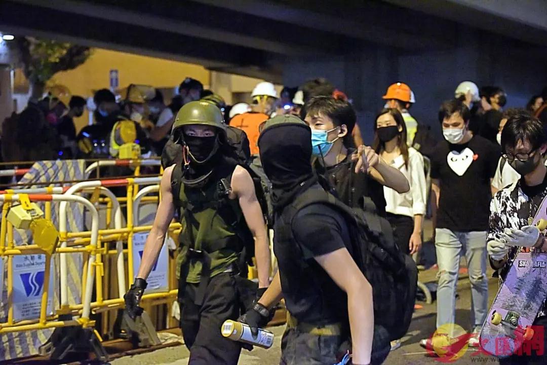杨逸朗(左)在警总门外上齐装备准备对警总进行冲击。来源：香港文汇网(资料图片)