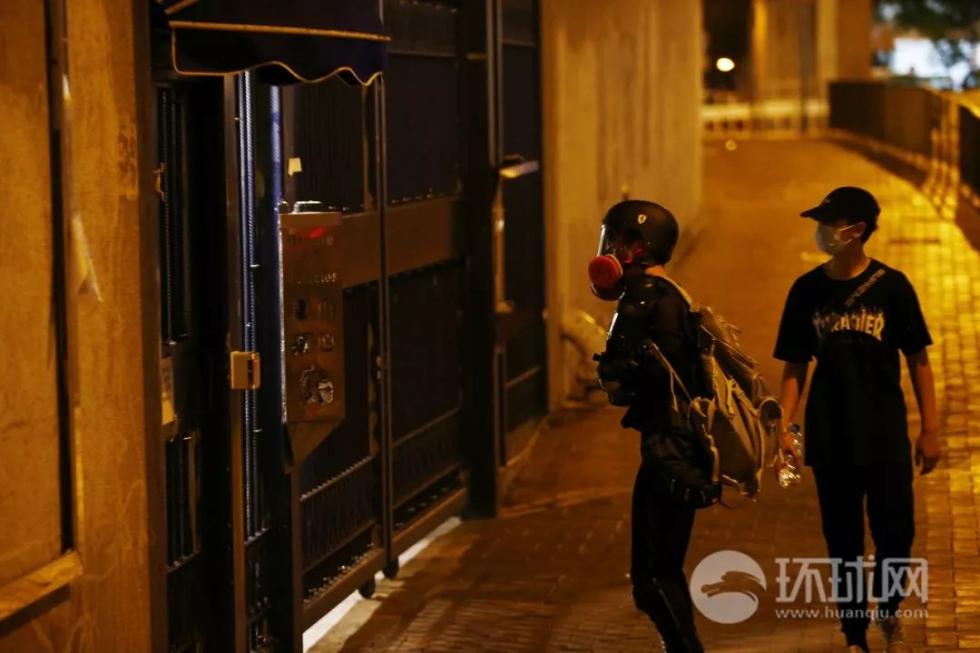 (23日晚，有头戴黑色头盔及面罩的黑衣人在葵涌警署前挑衅。摄：崔萌)