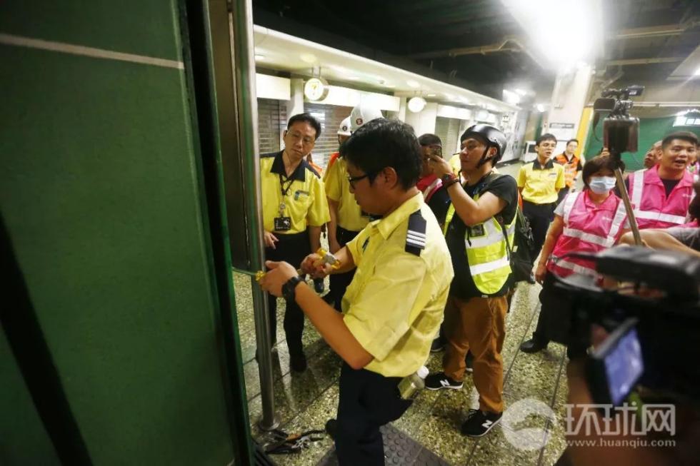 (23日晚，香港葵芳地铁站的港铁工作人员在关闭该站的闸门。摄：崔萌)