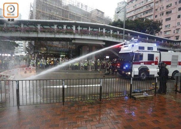 （25日18时05分，一辆水炮车向大河道路路障射水，速龙小队其后移除路障。图源：香港“东网”）