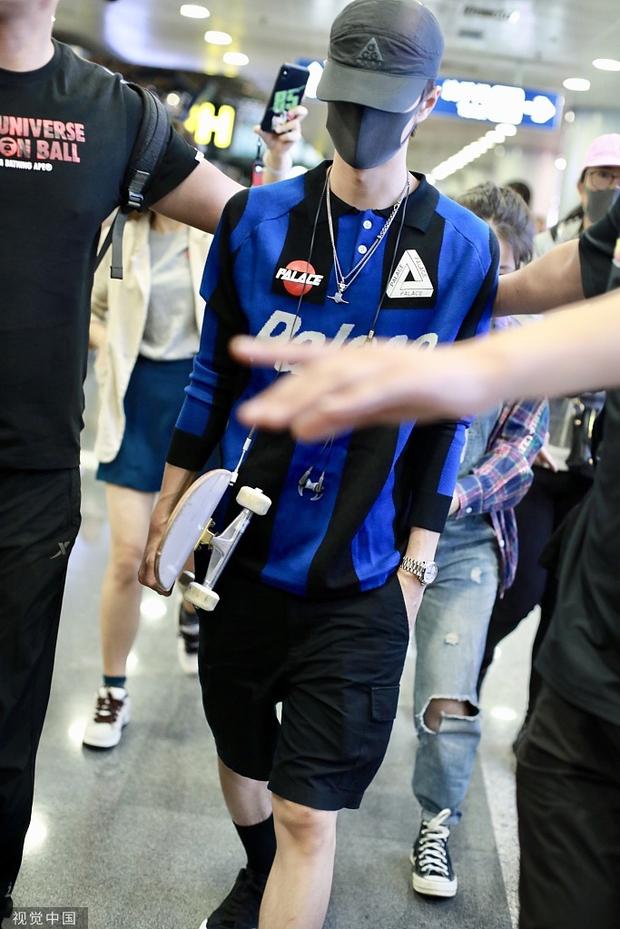 王一博带着黑色鸭舌帽，穿着蓝黑条纹的长袖上衣和黑色运动短裤，穿着打扮非常帅气。