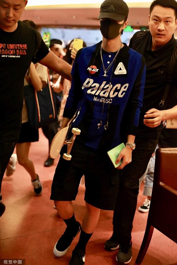 王一博黑鞋长筒袜很醒目，一路上他拿着滑板片刻都没放下。