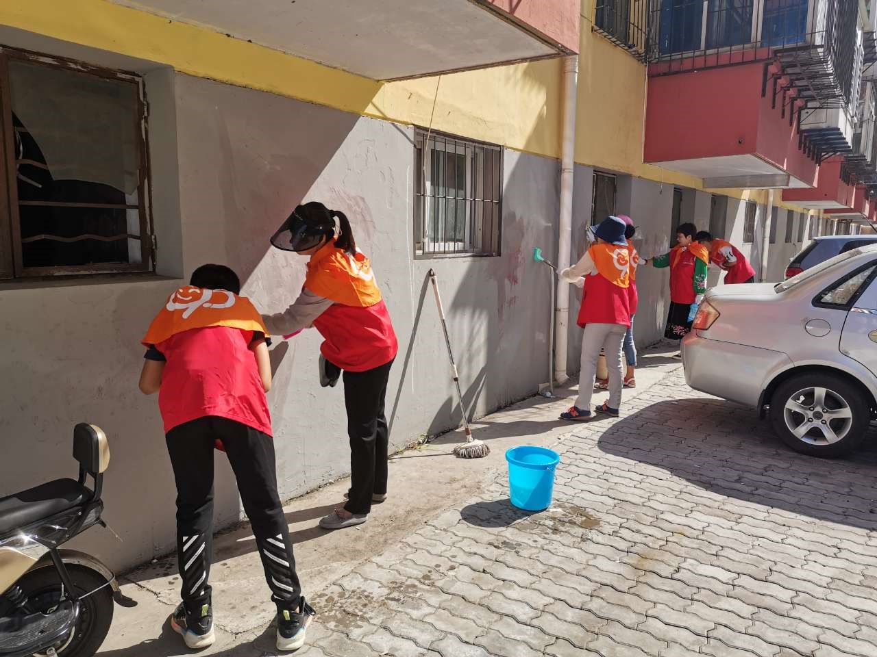 (秦皇岛市学雷锋公益服务中心志愿者在清理社区墙上的涂抹乱画)