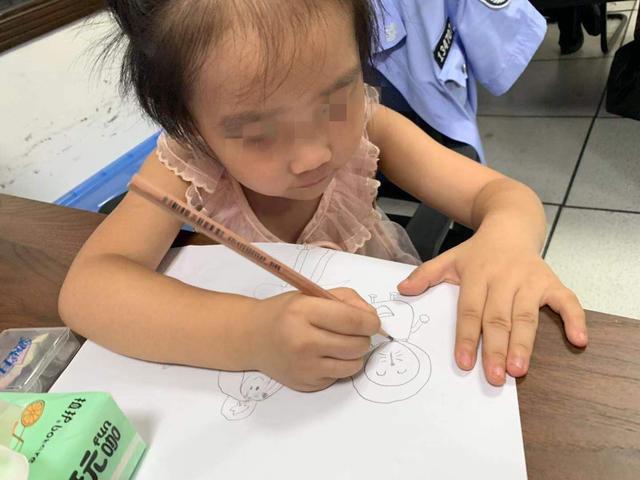 小女孩停止哭闹后，在白纸上画画。