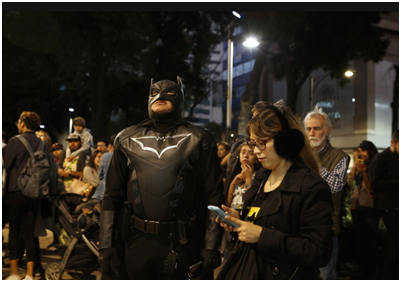 装扮成蝙蝠侠的粉丝在墨西哥的大楼前注视着标志 图源：美联社
