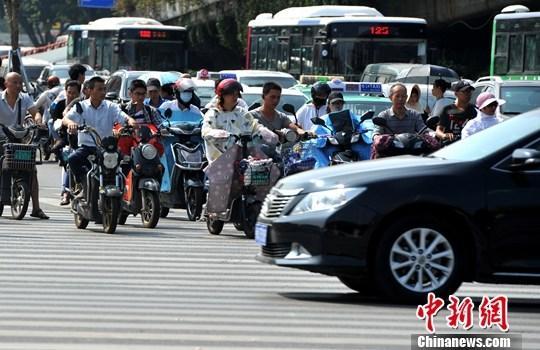 10月10日，福州街头，民众骑着电动自行车出行。中新社记者 张斌 摄