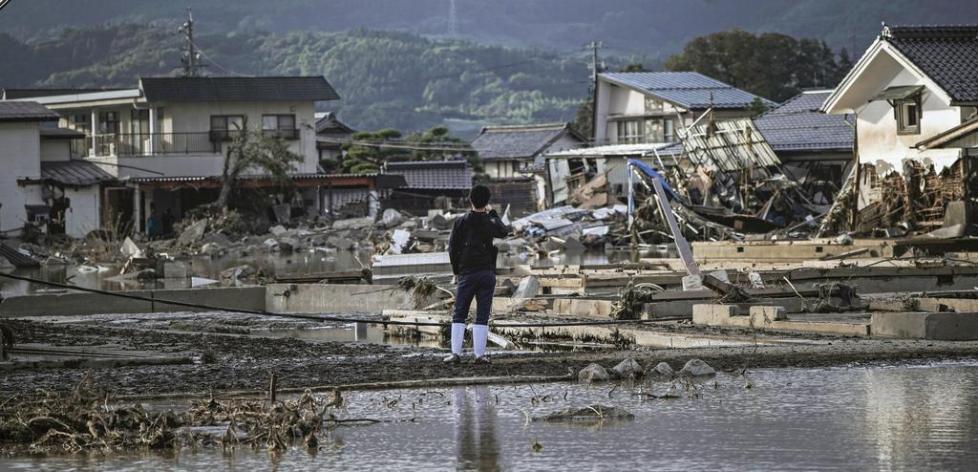 日本灾民站在因千曲川溃堤而遭受洪灾的住宅区前（《产经新闻》）