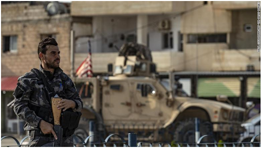 一美军车辆开过叙利亚士兵身旁 图源：CNN