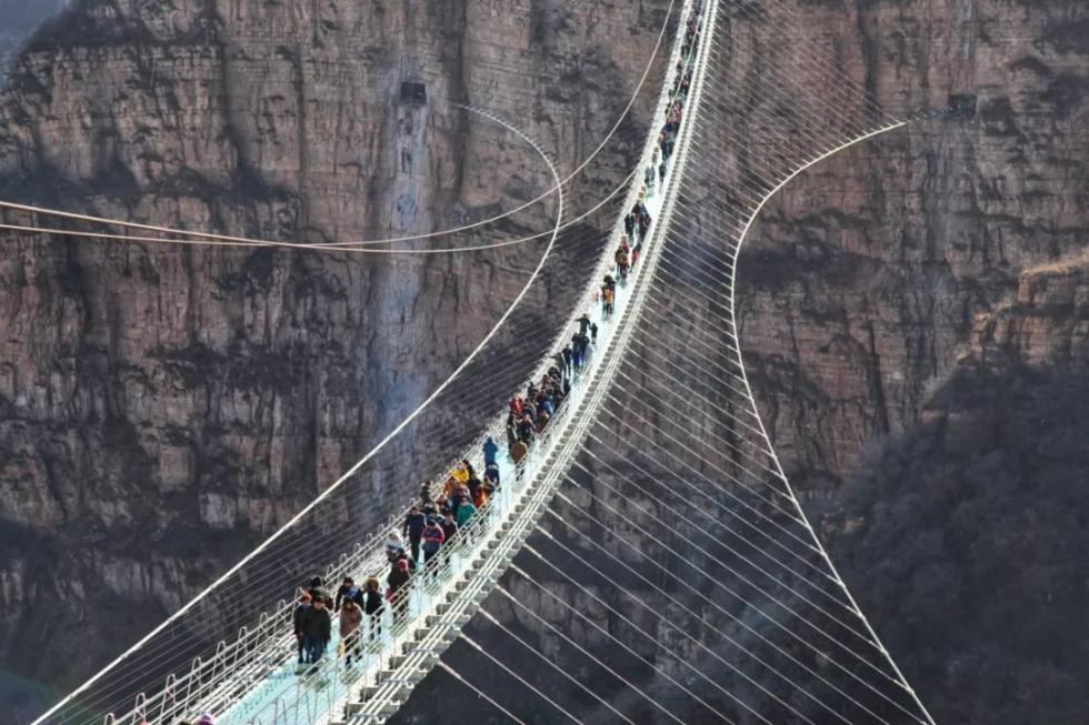 12月24日,游客在河北省平山县红崖谷景区悬跨式玻璃桥上体验