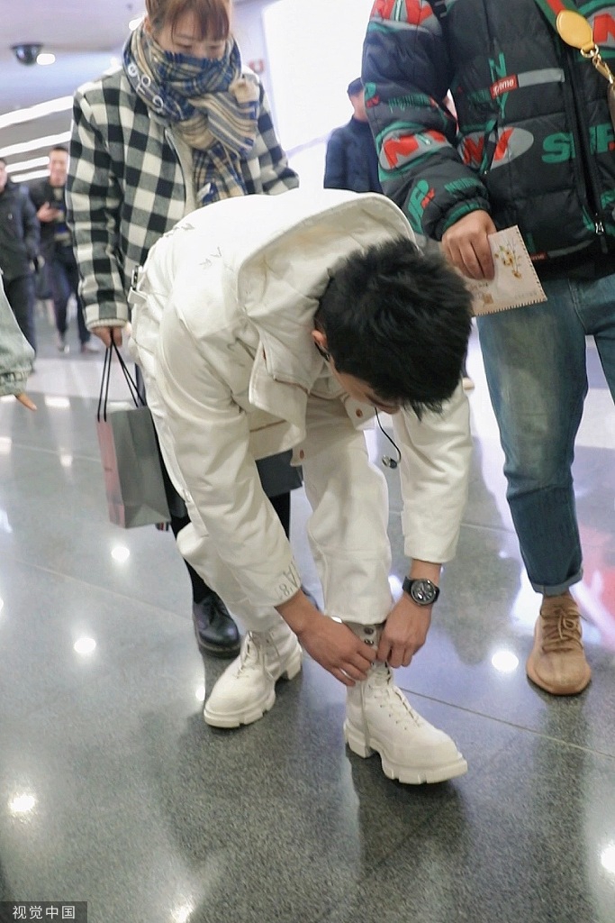 他全白look一展帅气身姿,他时而蹲下系鞋带,不断搓手御寒,对粉丝热情