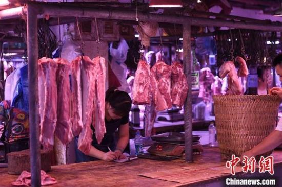 资料图为重庆一农贸市场内的商家挂满充足的猪肉。中新社记者 陈超 摄