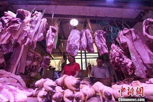 资料图：农贸市场内，商贩正在摆放猪肉。中新社记者 陈超 摄