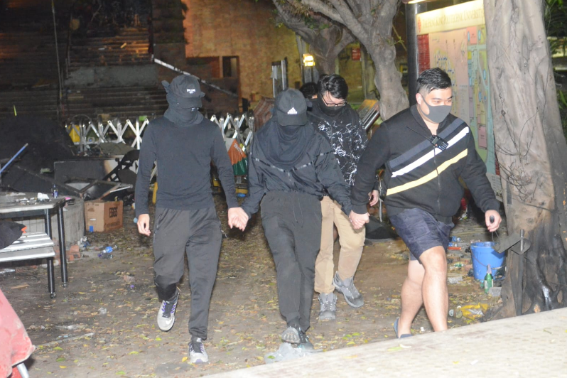 黑衣暴徒在义工带领下离开理工大学校园(图片来源：香港《星岛日报》)