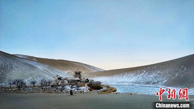 图为25日上午披上“银装”的敦煌鸣沙山月牙泉景区。 孙志成 摄