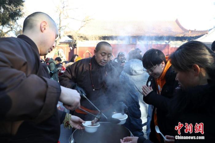 资料图：在北京雍和宫舍粥点前，人们排起百米长队等待领取腊八粥。中新社记者 韩海丹 摄