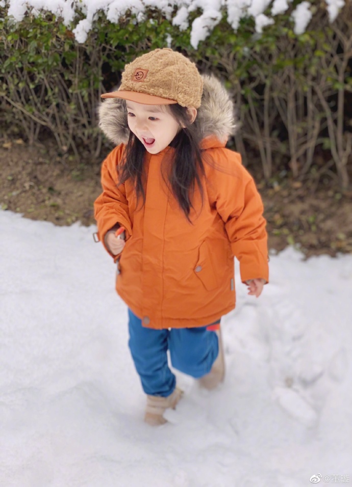 照片中的小酒窝头戴毛绒鸭舌帽,身穿橙色毛领外套和牛仔裤娇俏可爱