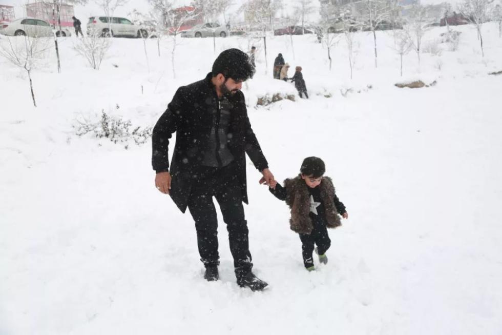 在阿富汗喀布尔，一名男子牵着孩子在雪中散步。 新华社发（拉赫马图拉摄）