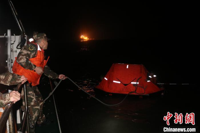图为海警人员利用救生筏接近搁浅渔船。 袁冠卿 摄