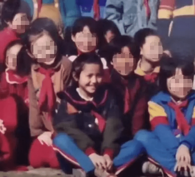 照片中佟丽娅双腿盘起坐在地上，笑容甜美五官精致。
