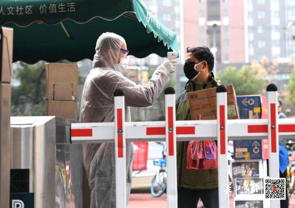 ▲2月3日，洪山区关山街道保利花园小区防疫卫士对居民进行体温测量 长江日报记者高勇 摄