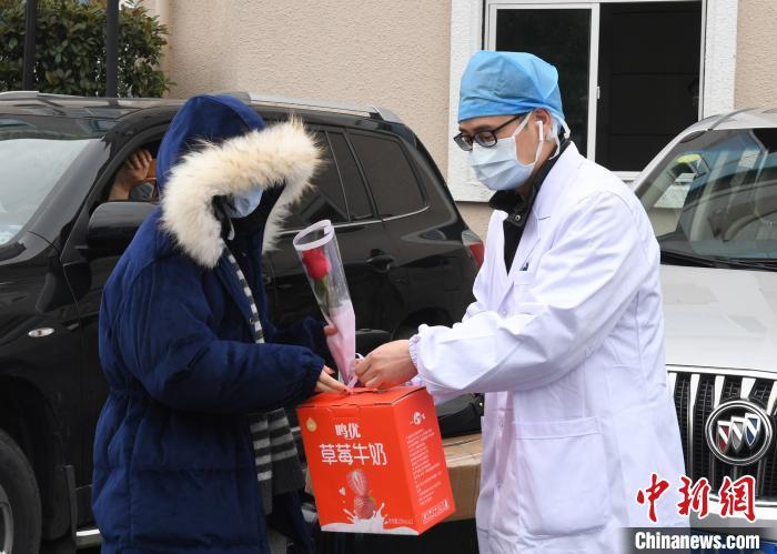 一位医护人员向出院的新冠肺炎患者赠送鲜花和营养品。 李晨韵 摄