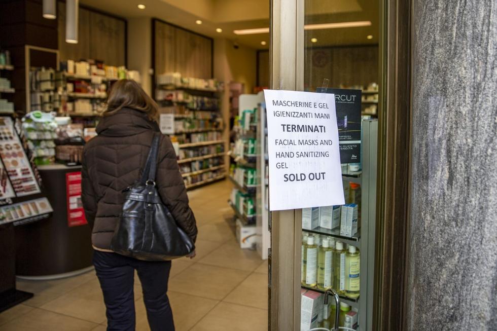 2月24日，米兰一家药店入口贴着告示，写着防护面罩和洗手液已售罄。图源：彭博社