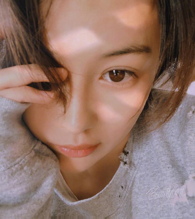 她身穿灰色居家服,托腮素颜对镜卖萌自拍,眼神温柔清澈,少女感十足