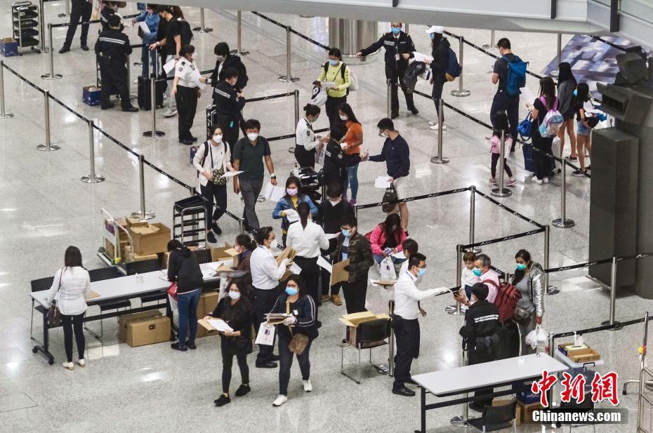 香港机场人员为抵港人士戴上手带作强制检疫监察