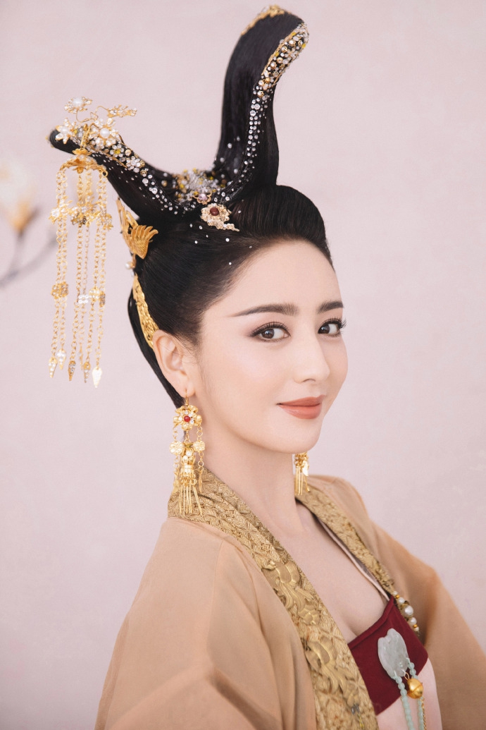 "照片中佟丽娅身穿粉金色系古装长袍,头挽发髻,搭配金色发饰,优雅高贵
